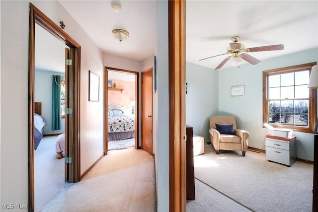 hall featuring baseboards and light carpet