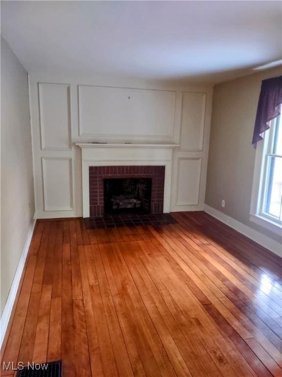 6846 Wakefield, Hiram, OH 44234 - unfurnished living room featuring hardwood / wood-style flooring, a brick fireplace, and baseboards