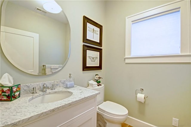 half bath featuring visible vents, toilet, and vanity