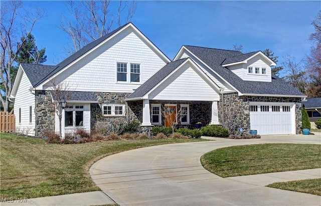 craftsman-style home with stone siding, a front yard, concrete driveway, and fence
