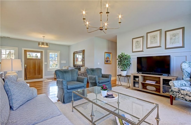 living room featuring baseboards, light wood-type flooring, and a notable chandelier