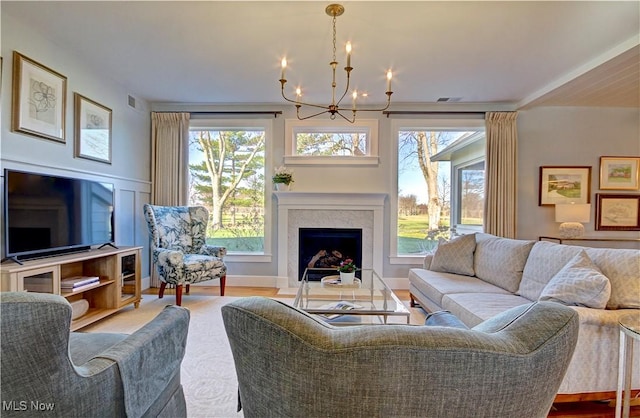living area with visible vents, a fireplace, wood finished floors, and an inviting chandelier
