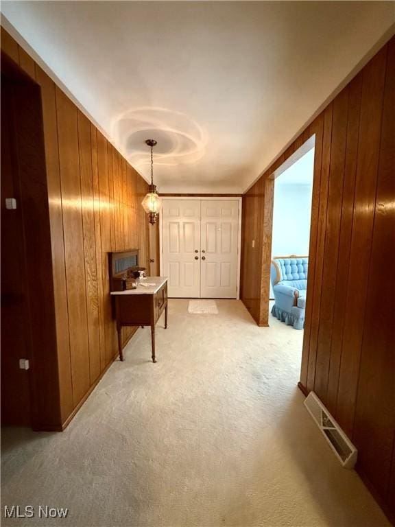 hall featuring visible vents, wood walls, and carpet