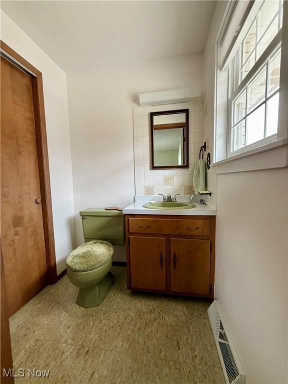 half bath featuring tile patterned floors, toilet, vanity, baseboards, and visible vents