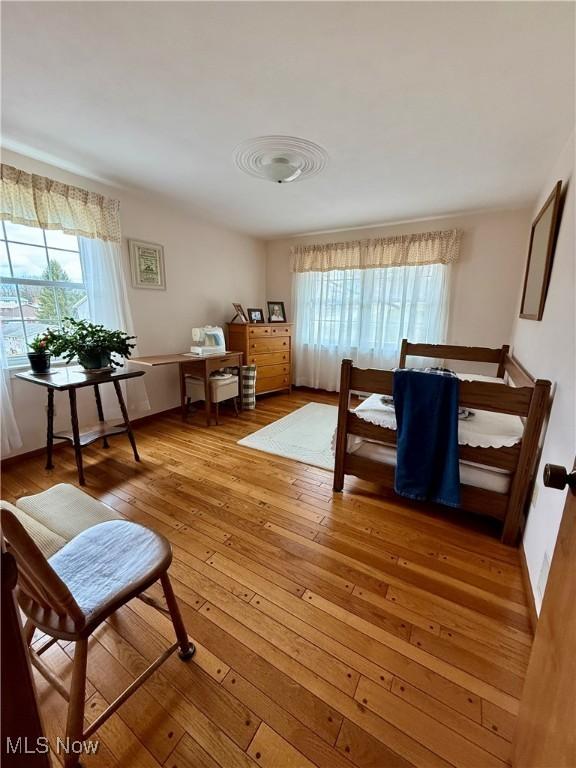 bedroom with multiple windows and hardwood / wood-style flooring
