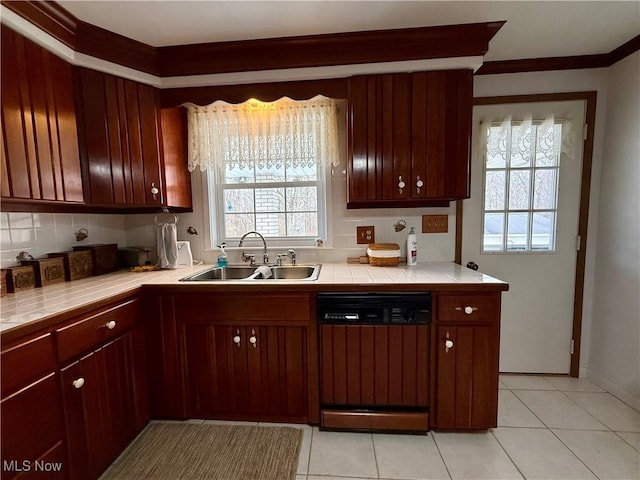 kitchen featuring dishwasher, a sink, tile countertops, and decorative backsplash