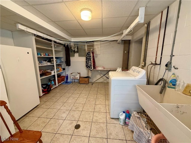laundry area with concrete block wall, independent washer and dryer, light tile patterned floors, a sink, and laundry area