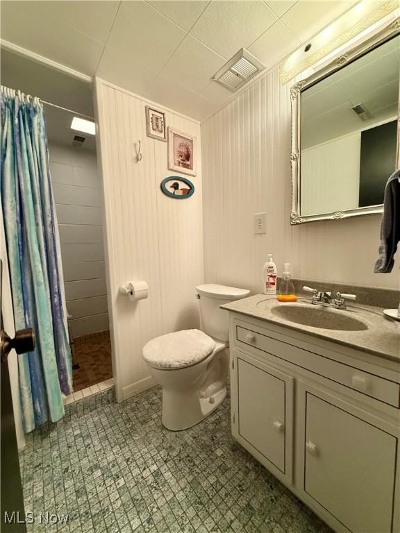 full bathroom featuring toilet, visible vents, tiled shower, and vanity
