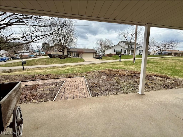 view of yard with driveway, an attached garage, and a residential view