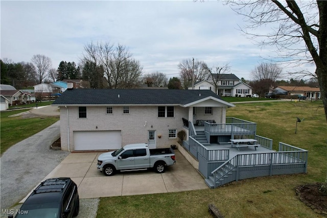 back of house featuring an attached garage, a lawn, a deck, brick siding, and driveway
