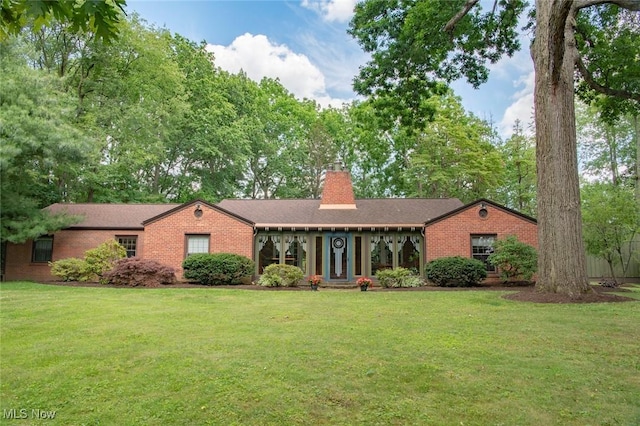 single story home with a chimney, a front yard, brick siding, and roof with shingles