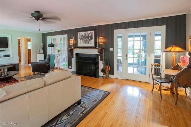 living room with a brick fireplace, crown molding, and a healthy amount of sunlight