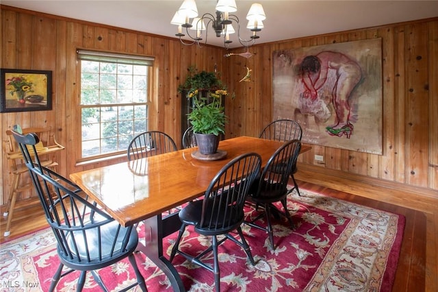 dining space with wood walls, an inviting chandelier, and wood finished floors