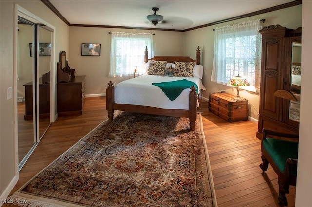 bedroom featuring wood finished floors, multiple windows, and crown molding