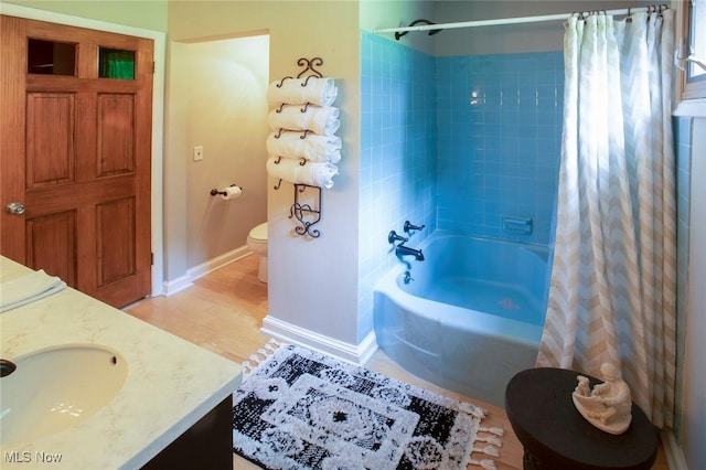 full bath featuring vanity, toilet, baseboards, shower / bath combo, and wood finished floors