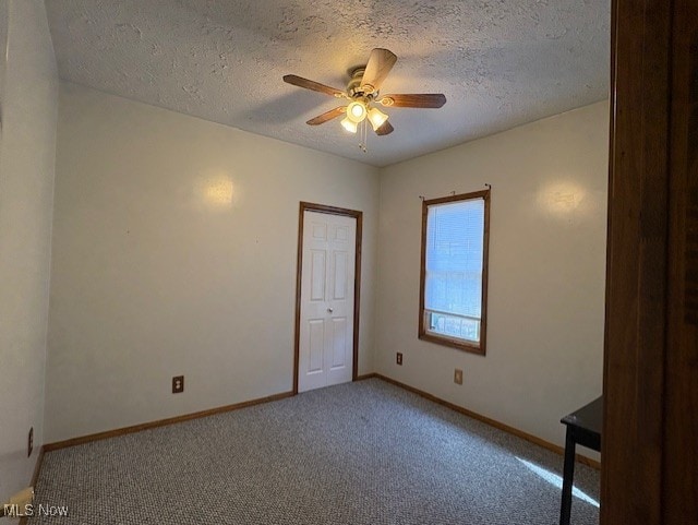 carpeted spare room with baseboards, a textured ceiling, and ceiling fan