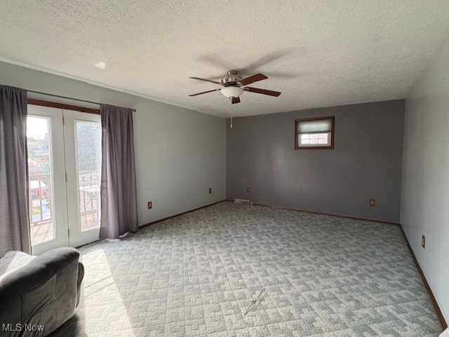 empty room featuring a ceiling fan, light carpet, baseboards, and a textured ceiling