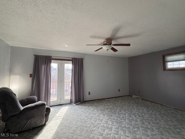 sitting room featuring a ceiling fan, carpet, baseboards, and a wealth of natural light