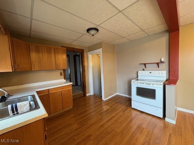 kitchen with light countertops, a sink, light wood-style floors, brown cabinetry, and electric range