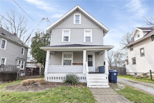 american foursquare style home featuring covered porch and fence
