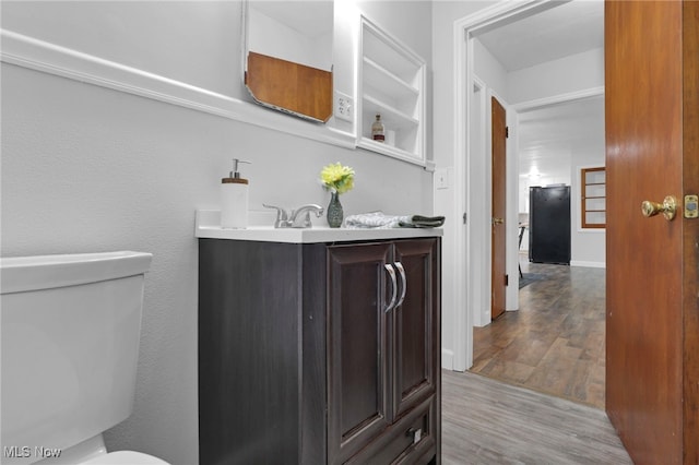 507 Beacon Rd, Newark, OH 43055 - half bathroom featuring toilet, vanity, and wood finished floors