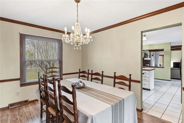 21242 Jonathan Dr, Strongsville, OH 44149 - dining room with a notable chandelier, crown molding, light wood finished floors, and visible vents