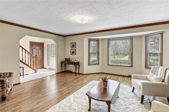 21242 Jonathan Dr, Strongsville, OH 44149 - living room featuring light wood-style floors, stairway, a textured ceiling, arched walkways, and ornamental molding