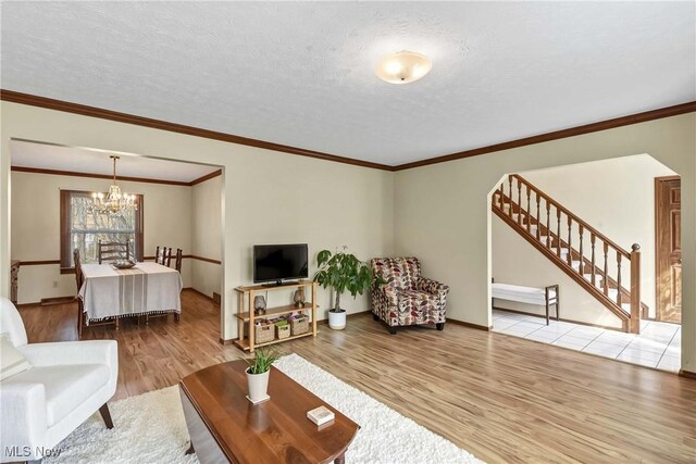 21242 Jonathan Dr, Strongsville, OH 44149 - living room with stairs, a textured ceiling, wood finished floors, and a notable chandelier
