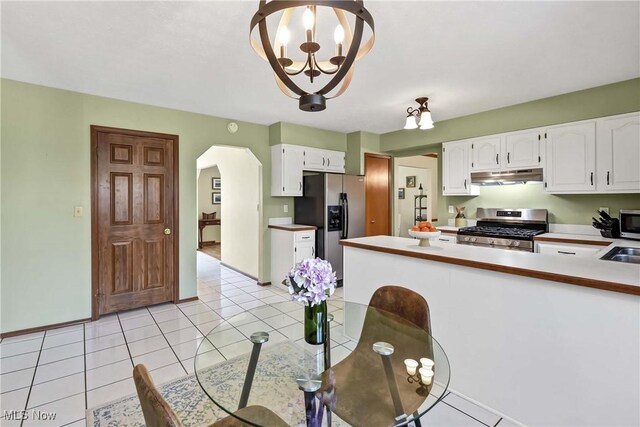 21242 Jonathan Dr, Strongsville, OH 44149 - kitchen featuring white cabinetry, arched walkways, stainless steel appliances, and under cabinet range hood