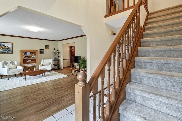 21242 Jonathan Dr, Strongsville, OH 44149 - staircase featuring a textured ceiling, wood finished floors, and crown molding