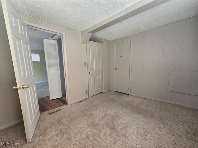 unfurnished bedroom with visible vents, carpet flooring, and a textured ceiling