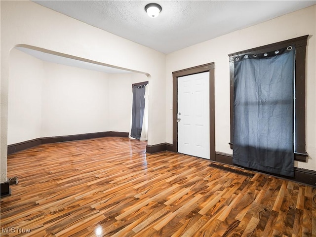unfurnished room with visible vents, a textured ceiling, baseboards, and wood finished floors