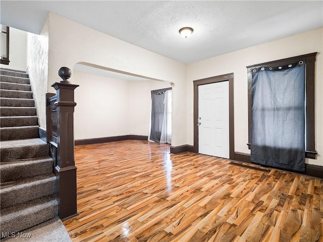 entrance foyer featuring stairs, wood finished floors, baseboards, and a textured ceiling