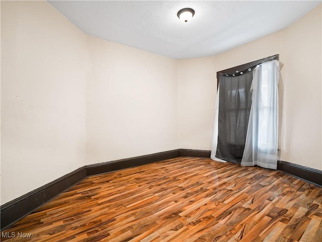 unfurnished room with baseboards and wood finished floors