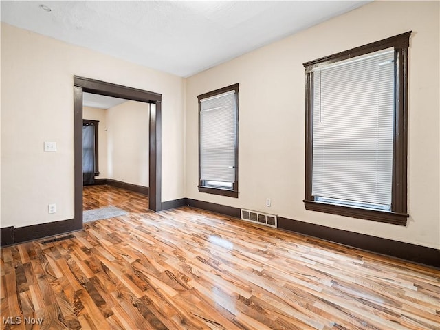 unfurnished room with wood finished floors, baseboards, and visible vents