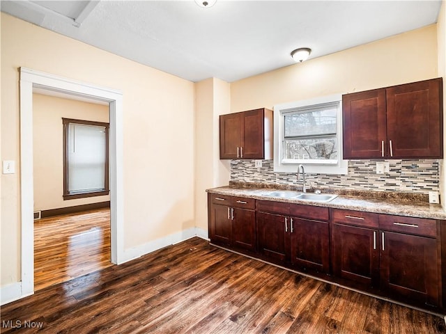 kitchen featuring baseboards, a sink, tasteful backsplash, and dark wood finished floors