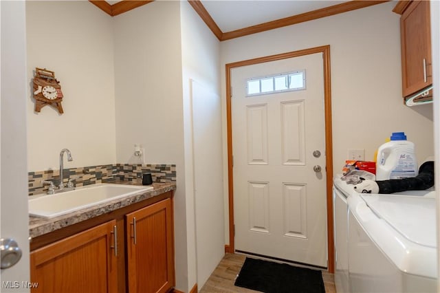 2409 Chelsea Dr SW, Canton, OH 44706 - clothes washing area featuring crown molding, light wood-type flooring, a sink, cabinet space, and washing machine and dryer