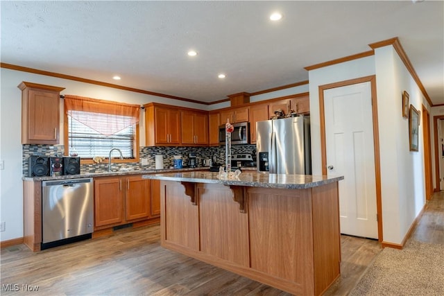 2409 Chelsea Dr SW, Canton, OH 44706 - kitchen with light wood finished floors, a center island with sink, tasteful backsplash, and appliances with stainless steel finishes