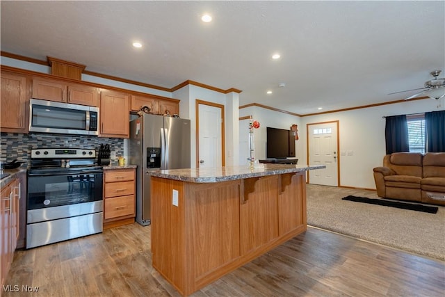 2409 Chelsea Dr SW, Canton, OH 44706 - kitchen featuring open floor plan, a breakfast bar area, light wood-type flooring, backsplash, and appliances with stainless steel finishes