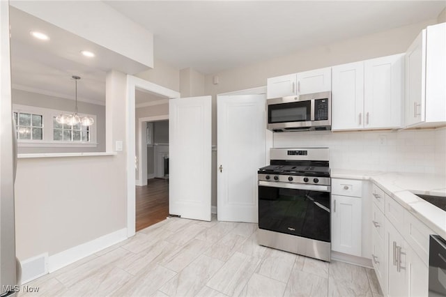3459 Helen Rd, Shaker Heights, OH 44122 - kitchen featuring a notable chandelier, light stone counters, stainless steel appliances, white cabinets, and decorative backsplash
