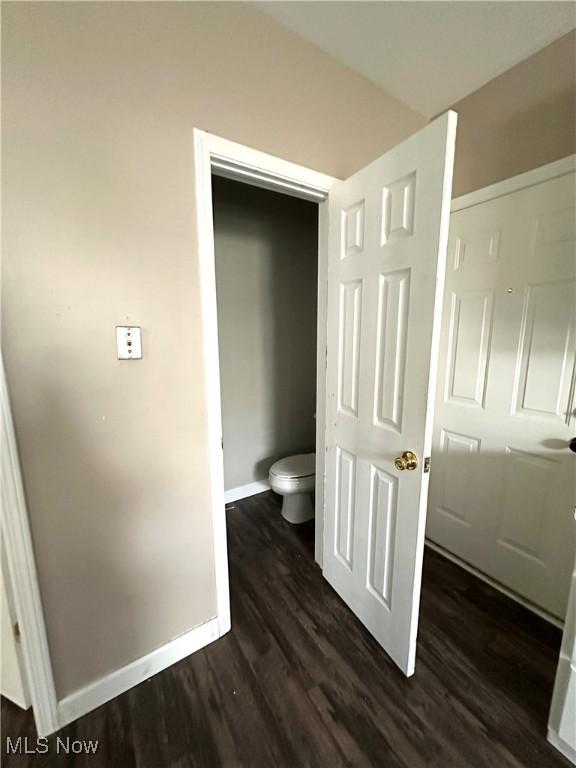 bathroom with baseboards, wood finished floors, and toilet