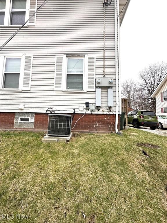 view of property exterior with a lawn and central AC