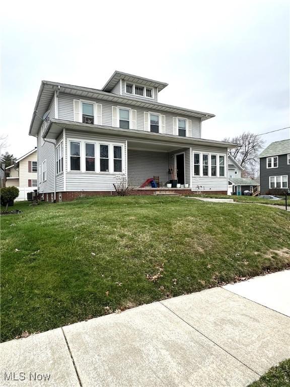 american foursquare style home featuring a front lawn