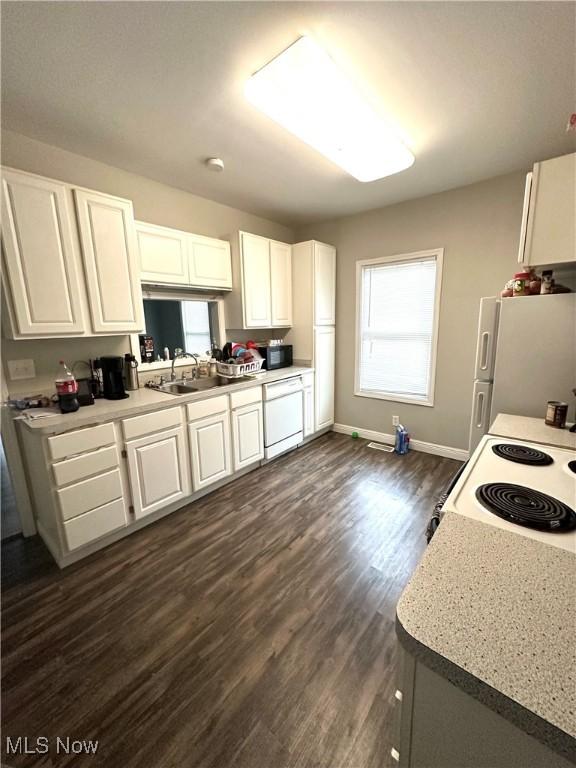 kitchen with white appliances, white cabinets, light countertops, and a sink