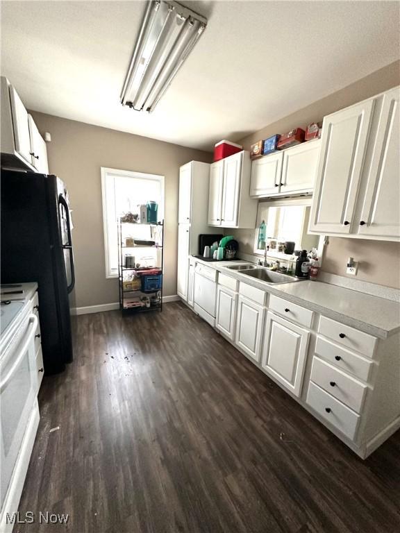 kitchen featuring light countertops, dark wood-type flooring, white cabinetry, a sink, and electric range