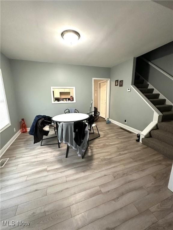 dining space featuring baseboards, wood finished floors, and stairway
