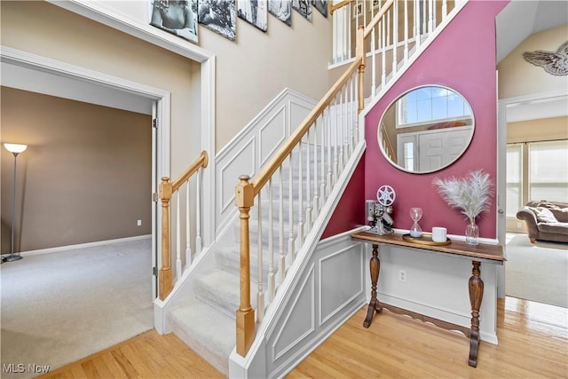 staircase featuring wood finished floors and a towering ceiling