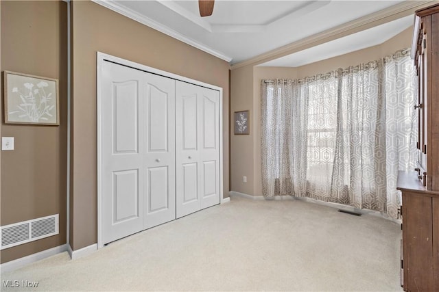 unfurnished bedroom featuring carpet floors, a closet, baseboards, crown molding, and ceiling fan