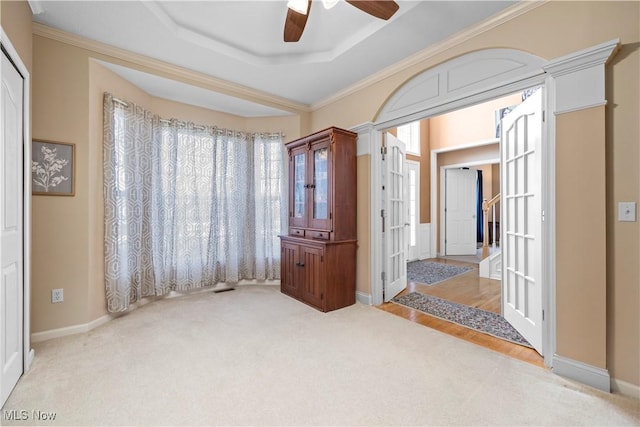 unfurnished bedroom with carpet, a tray ceiling, french doors, baseboards, and ornamental molding