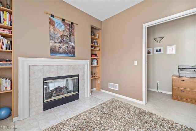 living area with built in shelves, baseboards, and a tiled fireplace